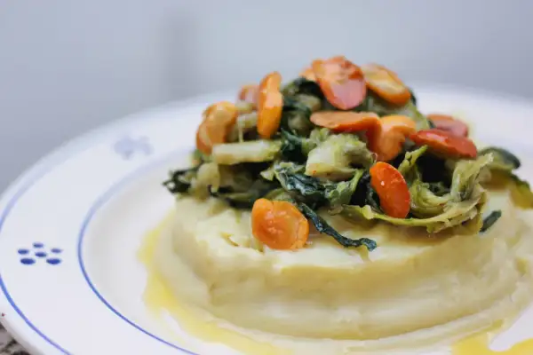 Purée crémeuse surmontée de fave et cicoria, un plat végétarien savoureux.