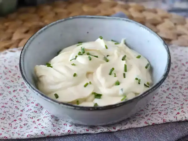 Un bol de mayonnaise sans huile, onctueuse et garnie de ciboulette fraîche. Parfaite pour accompagner vos plats.