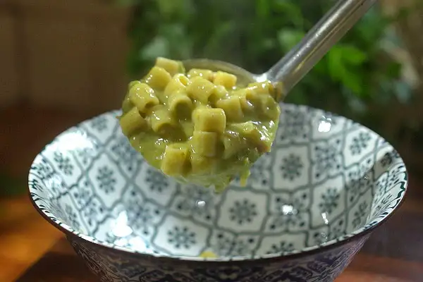 Une louche de pâtes ditalini dans une sauce crémeuse aux petits pois, parfaite pour une recette italienne simple et savoureuse.