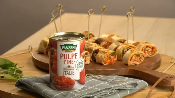 Délicieux wrap poulet garni de pulpe de tomate Panzani, présenté sur un plateau en bois avec des brochettes.