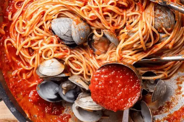 Spaghetti vongole tomate, un plat de pâtes aux palourdes et sauce tomate savoureuse, prêt à être dégusté.