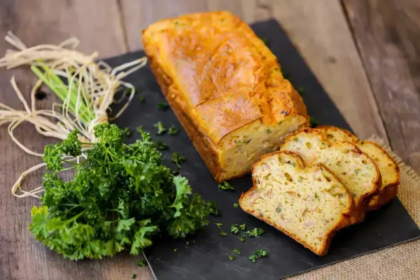 Un délicieux cake au thon, doré et moelleux, coupé en tranches. Accompagné de persil frais, parfait pour une recette facile.