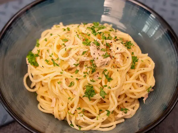 Délicieuses pâtes au thon, une recette simple et savoureuse, garnie de persil frais et de poivre noir.