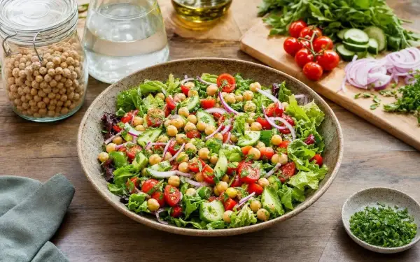 Salade composée fraîche et colorée avec pois chiches, tomates cerises, concombre et oignons rouges. Un délice sain et léger.