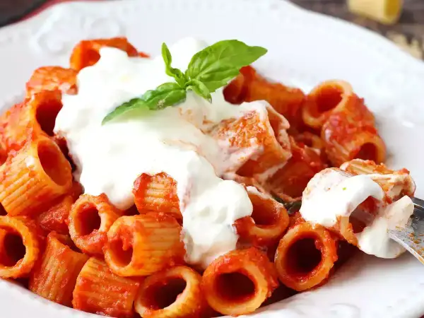 Pâtes rigatoni en sauce tomate, généreusement nappées de stracciatella crémeuse et garnies d'une feuille de basilic frais. Un délice !