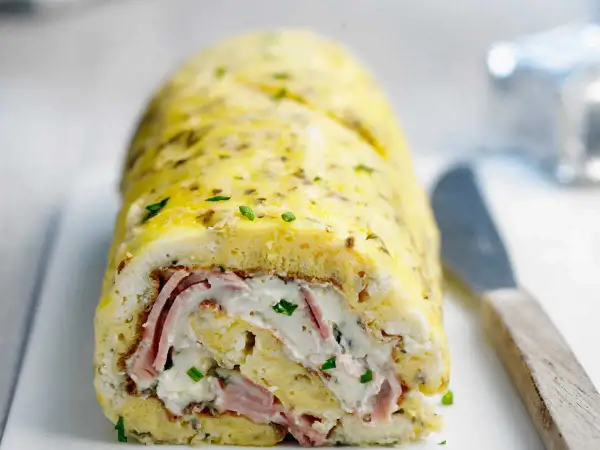Une savoureuse omelette roulée au four, garnie de jambon et de fromage frais, parsemée de ciboulette. Un délice !