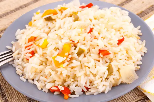 Une assiette de riz créole coloré avec des morceaux de poivrons rouges et jaunes.