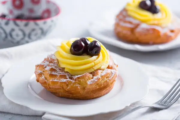 Zeppole di San Giuseppe, des pâtisseries italiennes garnies de crème pâtissière et de cerises, saupoudrées de sucre glace.
