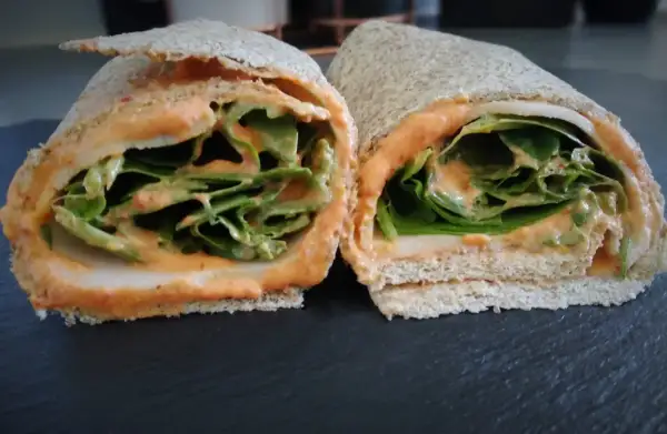 Deux moitiés d'un wrap jambon garni de feuilles de laitue croquantes et d'une sauce crémeuse.