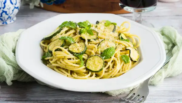 Spaghetti alla Nerano, un plat de pâtes crémeux aux courgettes et à la menthe fraîche, garni de parmesan râpé.
