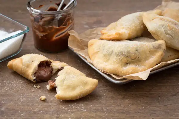 Des panzerotti nutella dorés et saupoudrés de sucre, un délice gourmand prêt à être dégusté.