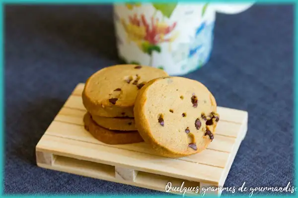 Pile de biscuits au café parsemés de pépites de chocolat, sur une petite palette en bois.