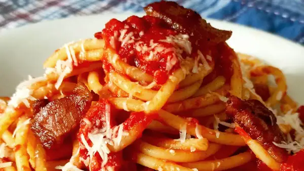 Un plat de pâtes amatriciana, avec des morceaux de guanciale croustillant, une sauce tomate riche et du fromage râpé.